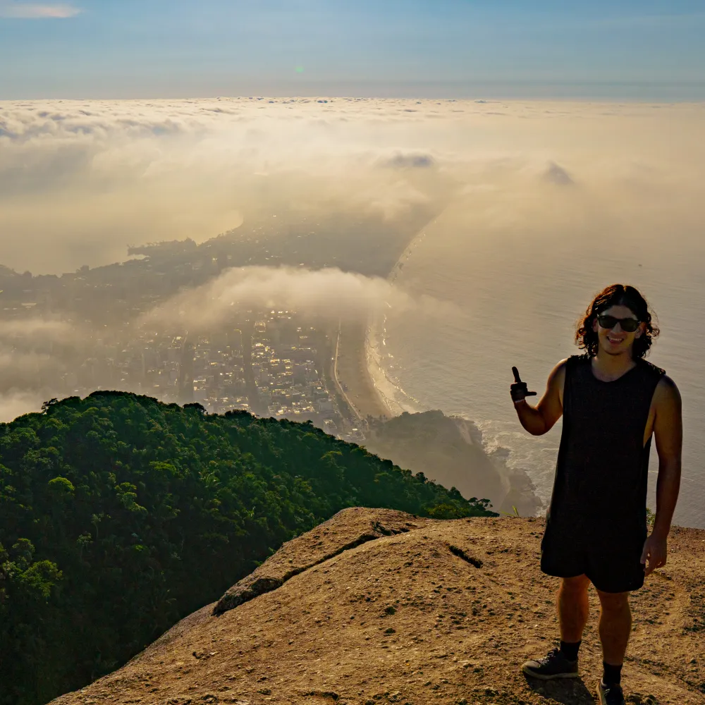 Kaya on a rock summit above the Rio coastline and clouds
